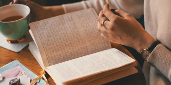 pexels-photo-3363111-3363111 A woman writes in a journal while enjoying a cup of coffee at a wooden table.